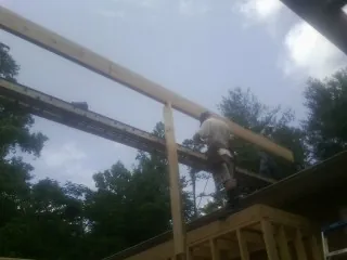 Carpenter setting a ridge beam over a new addition frame — Ice Dam Removal by Roofing Brothers in Halsey