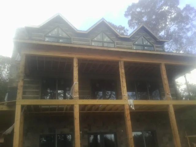 Dormers and porch framing on a large log home under construction — Roof Coating work by our crew in Halsey