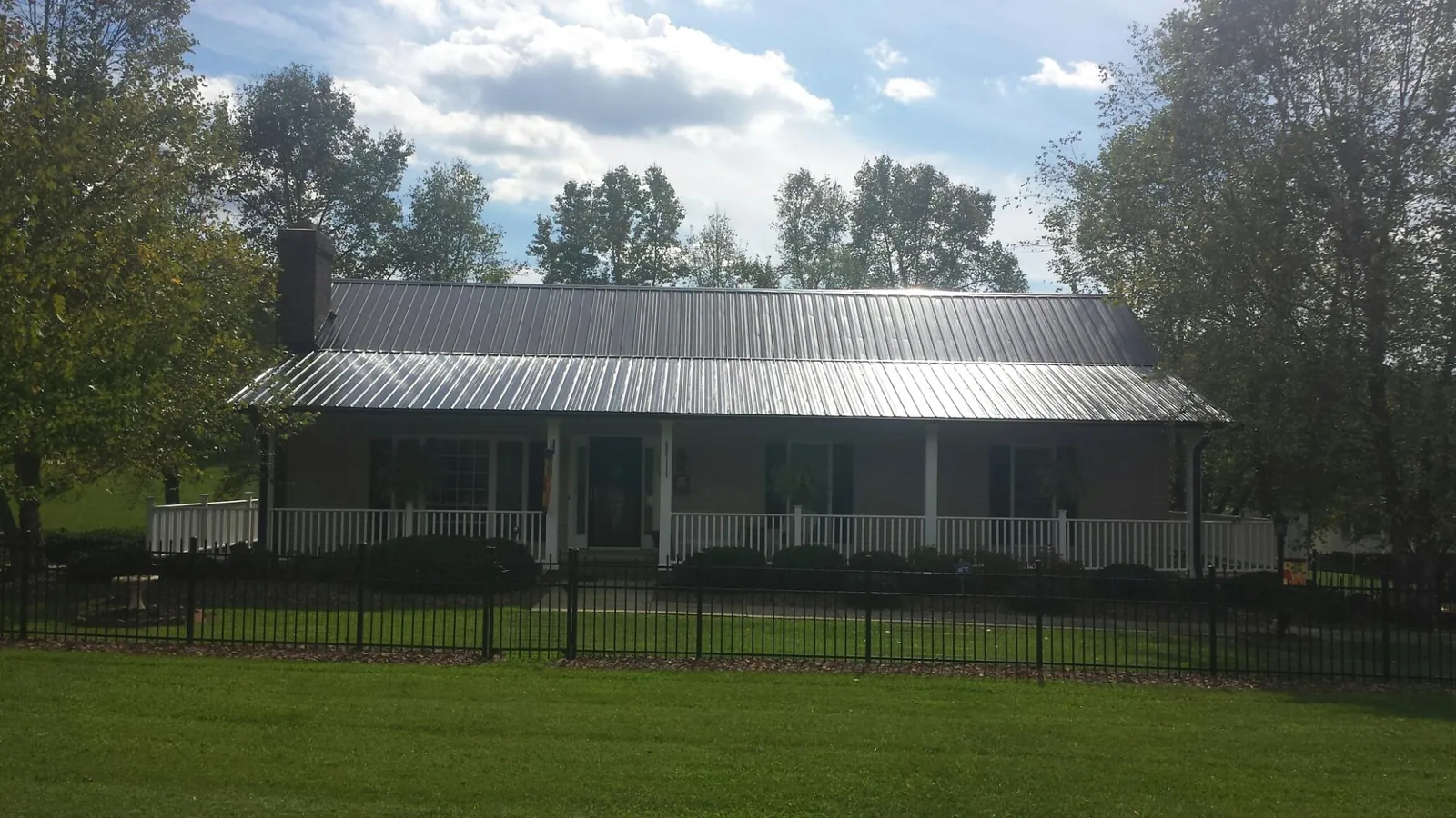 Gray metal roof on a brick ranch with a full width front porch — Gutter Guard Installation work by our crew in Halsey