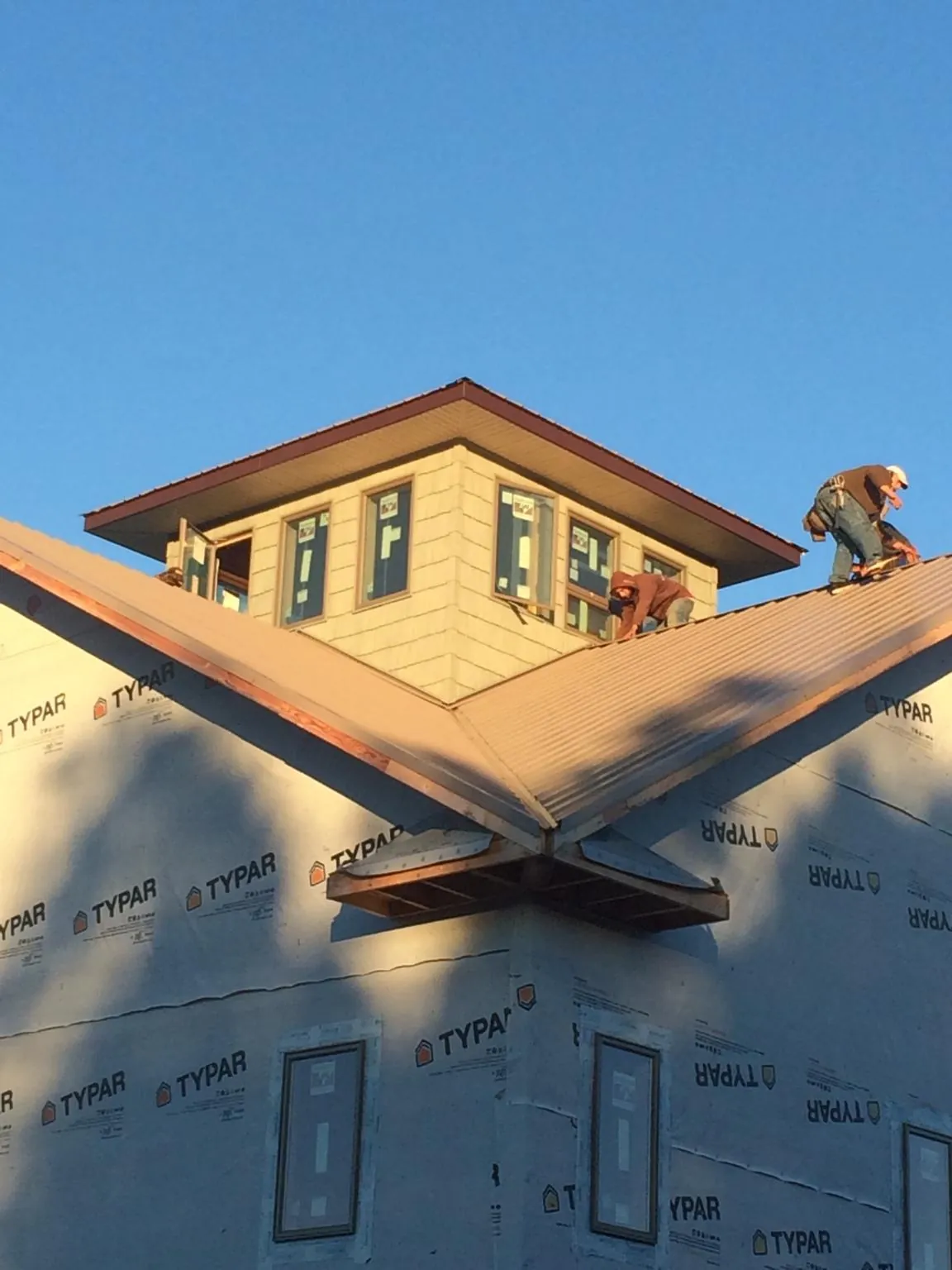 Roofers working around a rooftop cupola on a new metal roof at sunset — Roof Waterproofing in Halsey by Roofing Brothers